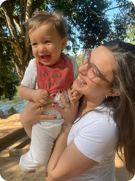 Sara com Miguel no colo, sorrindo em um momento de carinho